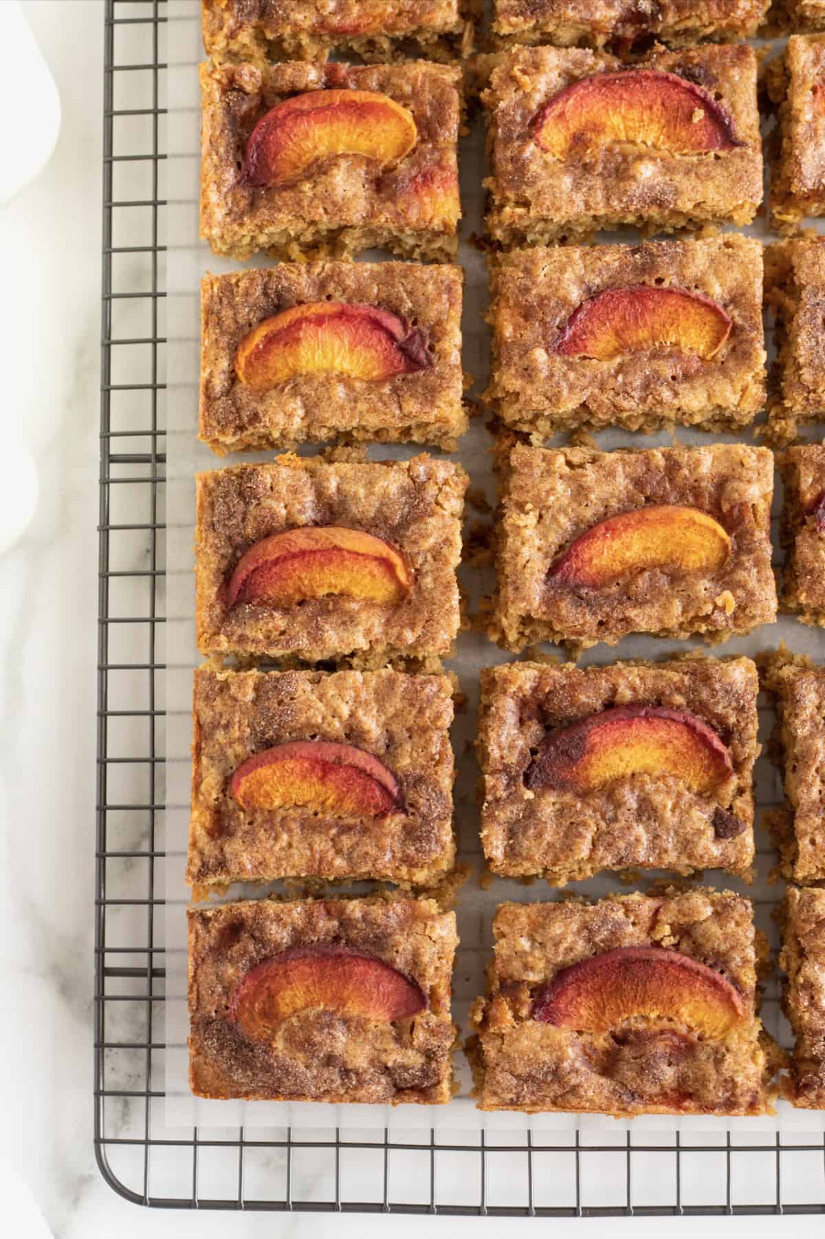 Peach Oatmeal Bars cut into 18 equal squares on a parchment covered cooling rack.