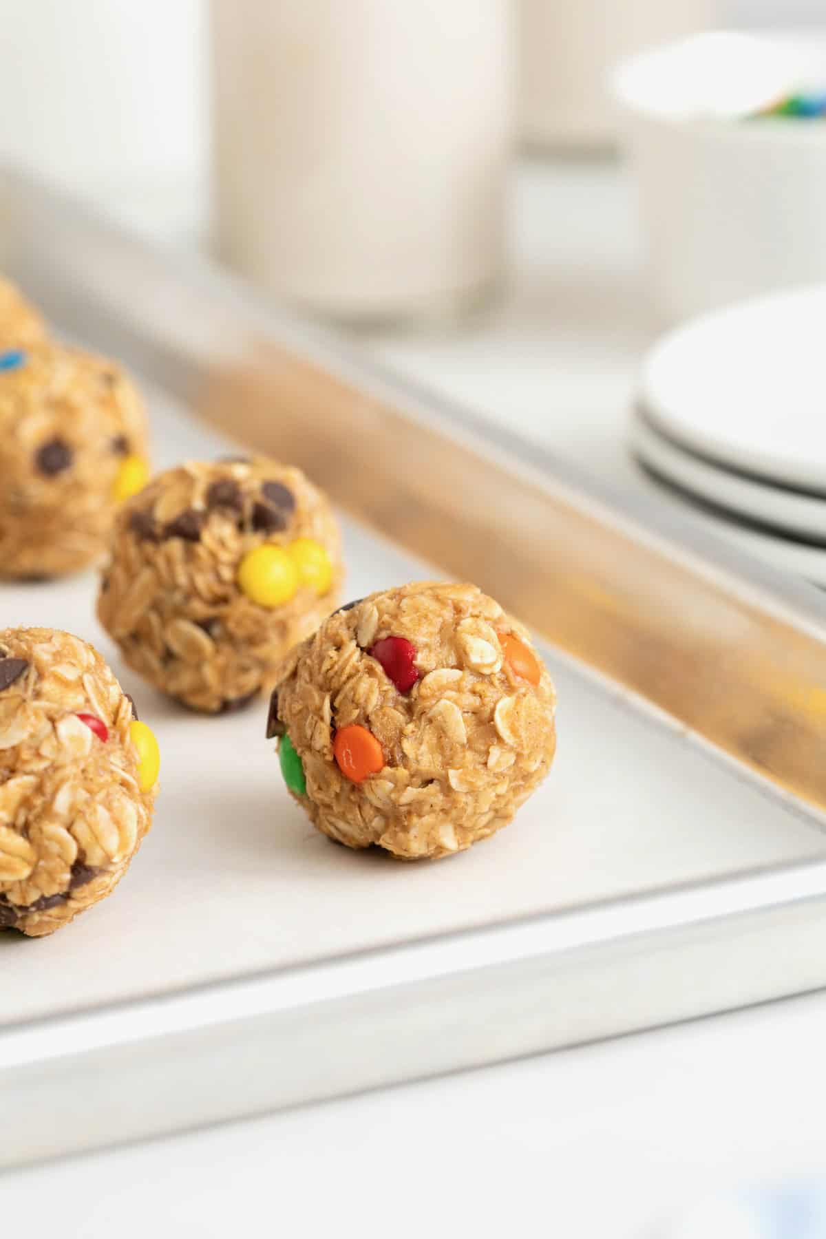 Monster cookie balls on a parchment lined aluminum baking sheet.