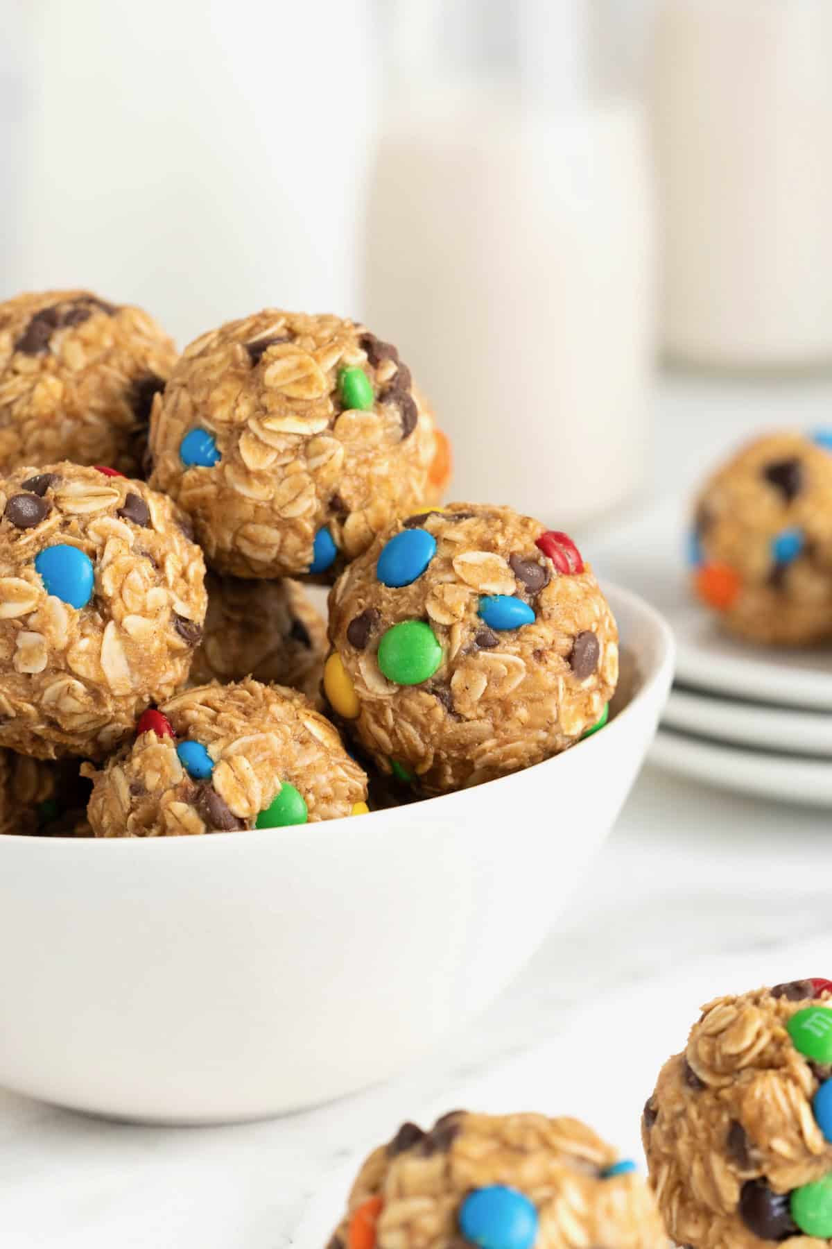 A white bowl of no-bake monster cookie balls on a white marble counter.