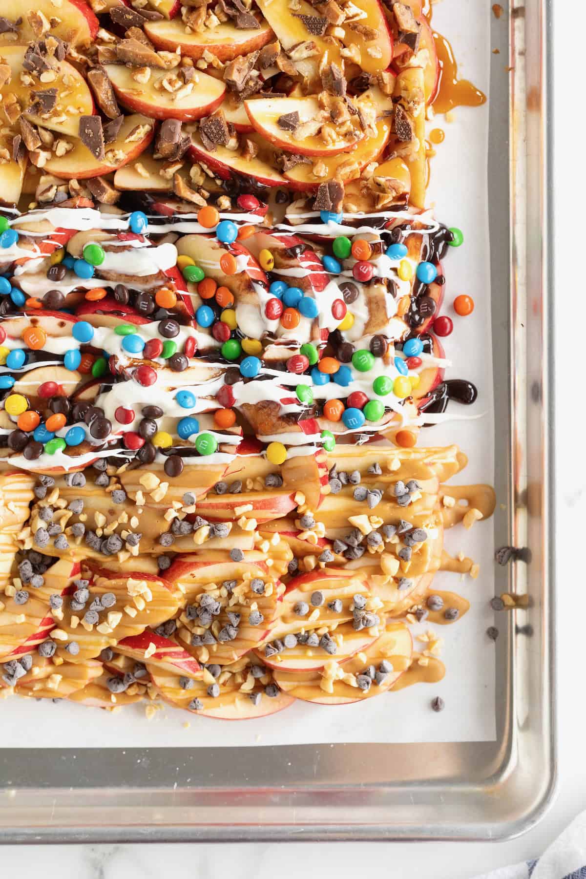 A parchment lined aluminum baking sheet covered with apple nachos.
