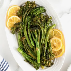 A white oval serving platter of broccolini and lemon slices.